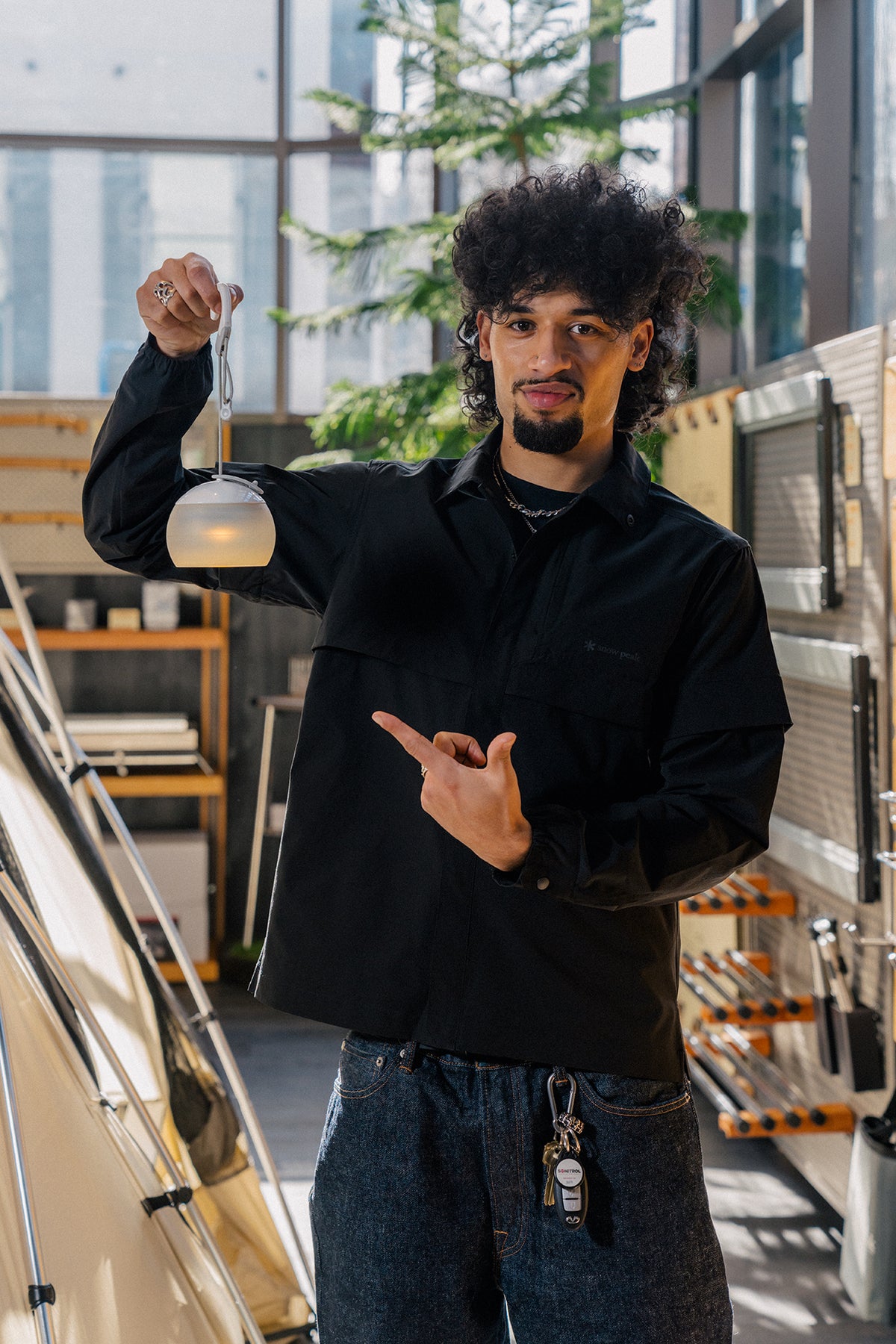 A retail associate in Portland, Oregon wearing a snow peak shirt and holding a snow peak hozuki lantern
